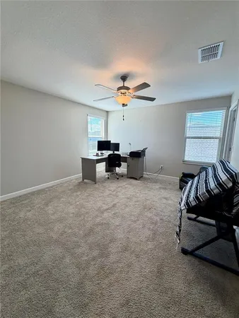 a view of a workspace with furniture and a ceiling fan