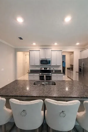 a kitchen with stainless steel appliances granite countertop a sink a stove a microwave a refrigerator and white cabinets