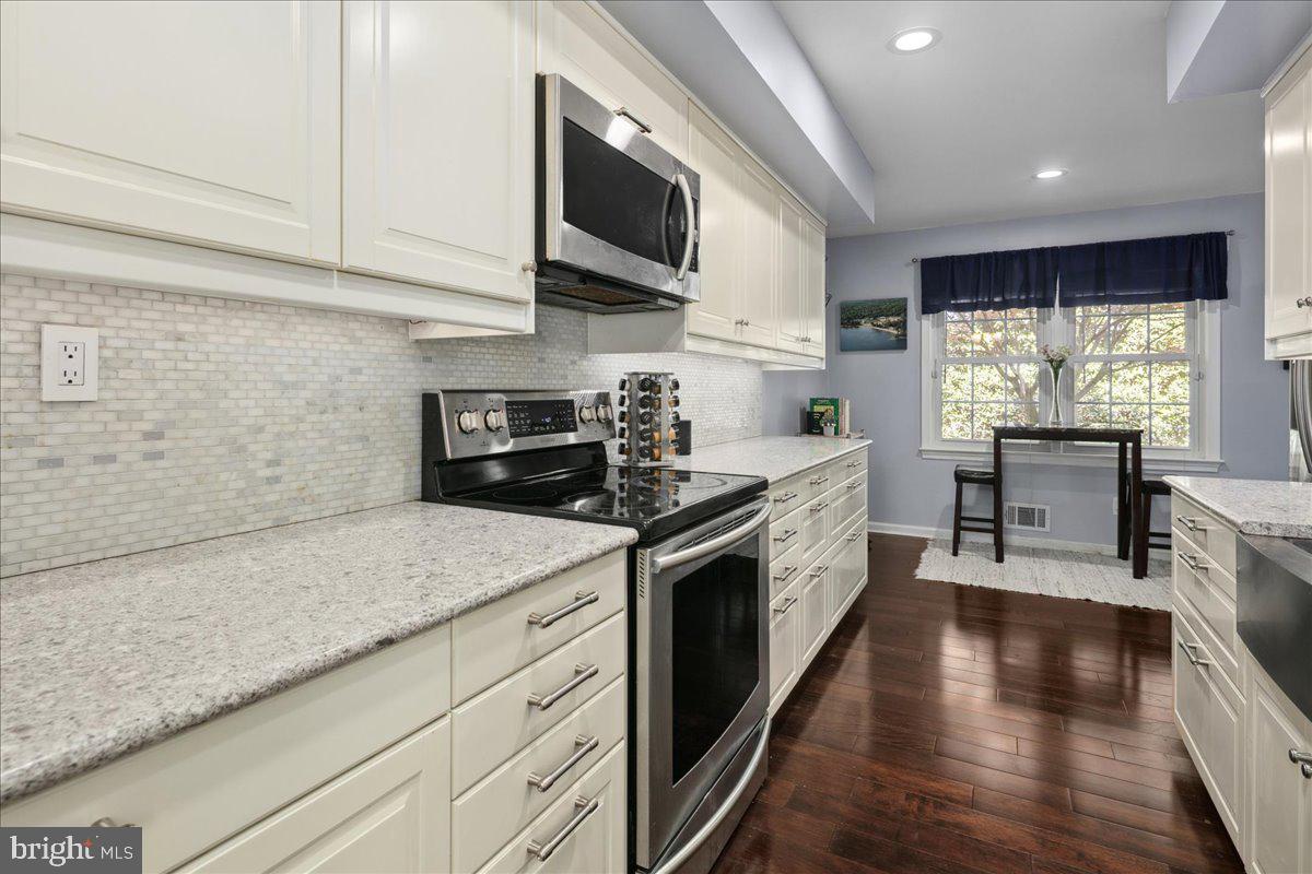 9623 Blake Lane Fairfax, VA 22031 - Photo 20 of 60 a kitchen with granite countertop kitchen island stainless steel appliances a stove sink microwave and cabinets