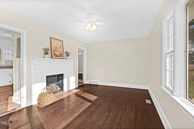 a view of a livingroom with a fireplace a chandelier and wooden floor