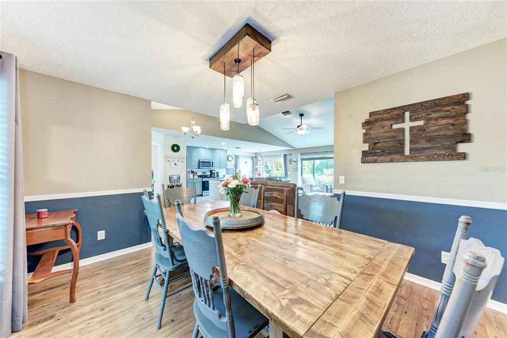 4608 Oliver Manor Drive Parrish, FL 34219 - Photo 13 of 45 a dining room with wooden floor a chandelier a wooden table and chairs