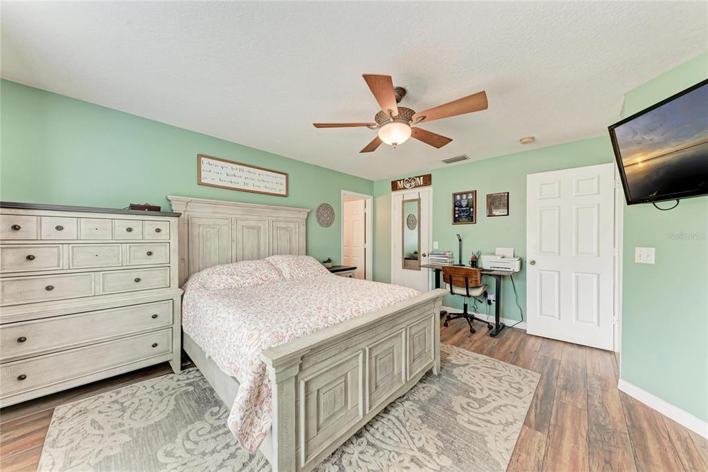 4608 Oliver Manor Drive Parrish, FL 34219 - Photo 16 of 45 a bedroom with a large bed a chandelier and a dresser