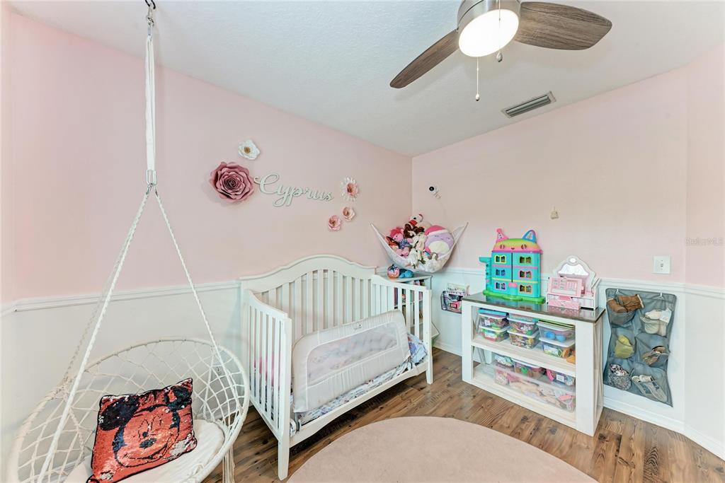 4608 Oliver Manor Drive Parrish, FL 34219 - Photo 21 of 45 a bedroom with furniture a baby crib and a wooden floor