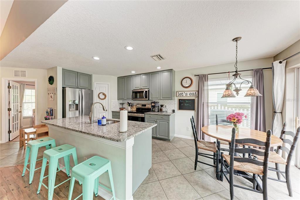 4608 Oliver Manor Drive Parrish, FL 34219 - Photo 8 of 45 a kitchen with stainless steel appliances kitchen island granite countertop a dining table chairs and a refrigerator