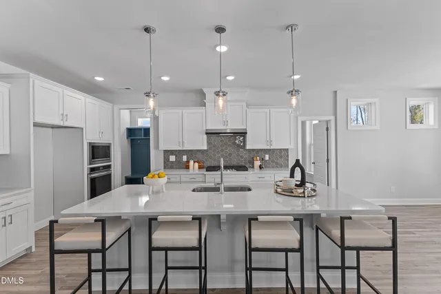 a kitchen with stainless steel appliances kitchen island granite countertop a dining table chairs and white cabinets