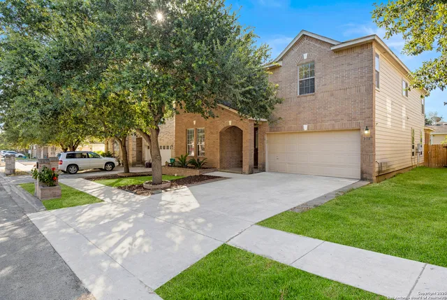 a view of a house with a yard and large tree