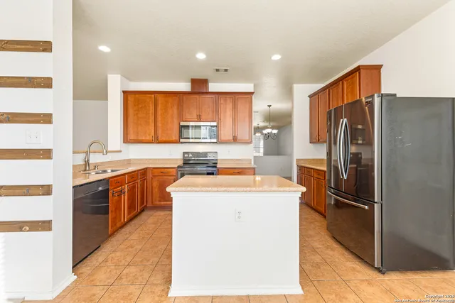 a kitchen with stainless steel appliances granite countertop a refrigerator a sink and a stove