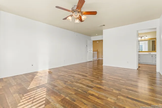 a view of a room with wooden floor and a ceiling fan