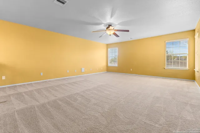 a view of a big room with windows and chandelier fan
