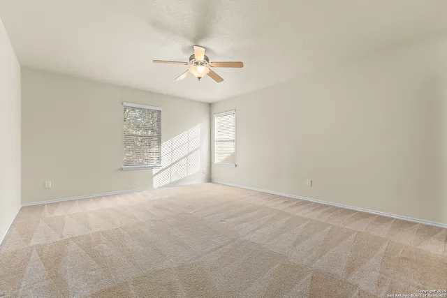an empty room with windows and fan