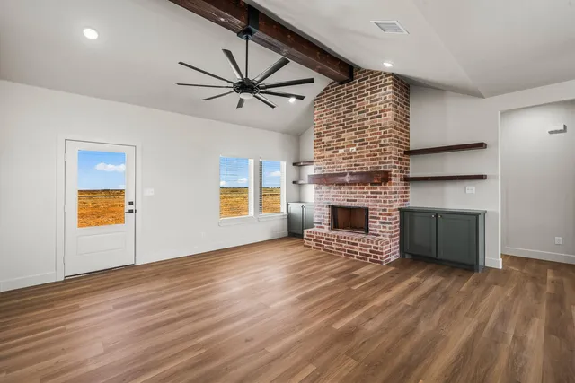 a living room with a fireplace furniture a ceiling fan and a window