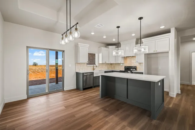 a kitchen with kitchen island granite countertop a sink a stove and cabinets