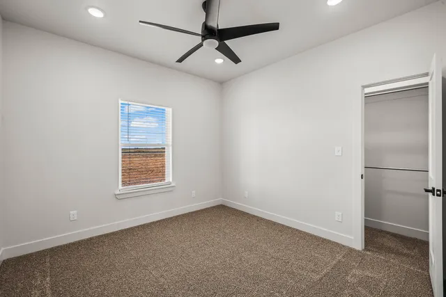 an empty room with a ceiling fan and carpet