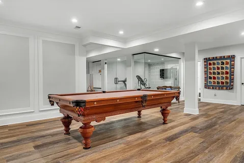 a room with wooden floor pool table furniture and windows