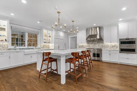 a kitchen with stainless steel appliances kitchen island granite countertop a table chairs sink and cabinets