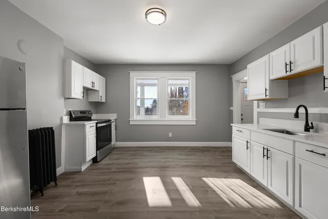 a kitchen with granite countertop a stove a sink and a refrigerator