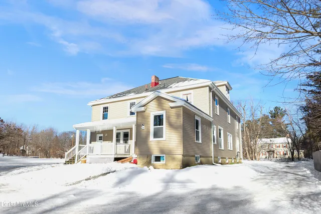 a view of a white building among the street with houses