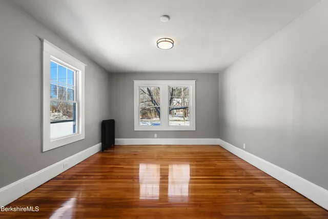 a view of an empty room with a window and wooden floor