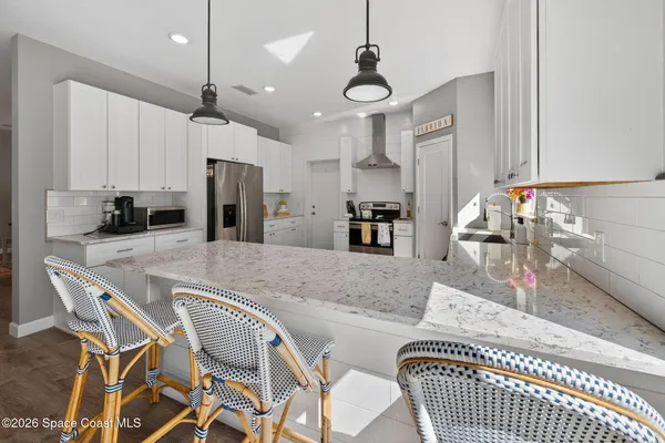a kitchen with kitchen island a stove a chandelier a dining table and chairs