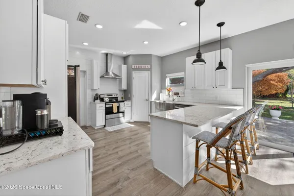a kitchen with stainless steel appliances granite countertop a kitchen island a stove a refrigerator a oven a sink a dining table and chairs with wooden floor