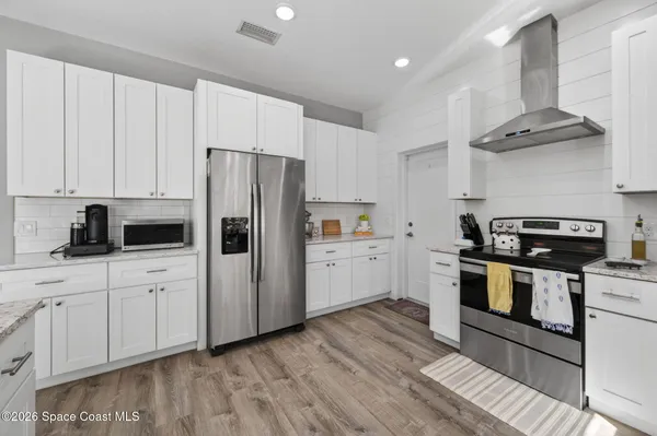 a kitchen with stainless steel appliances a stove a sink and white cabinets