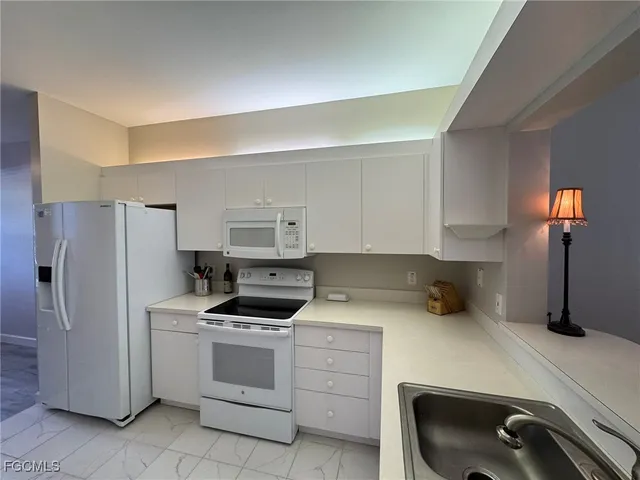 a kitchen with a refrigerator and white cabinets