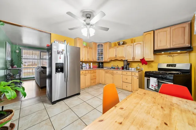 a kitchen with stainless steel appliances kitchen island granite countertop a refrigerator a stove a sink a dining table and chairs with wooden floor