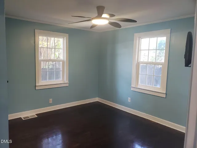 a view of an empty room with wooden floor and a window