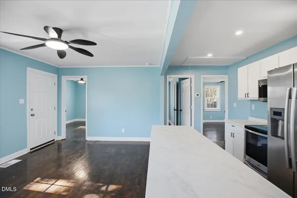 a view of a kitchen with a sink cabinet a refrigerator and windows