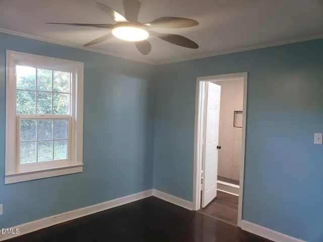 an empty room with wooden floor closet and windows