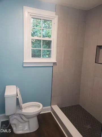 a white toilet sitting in a bathroom next to a window