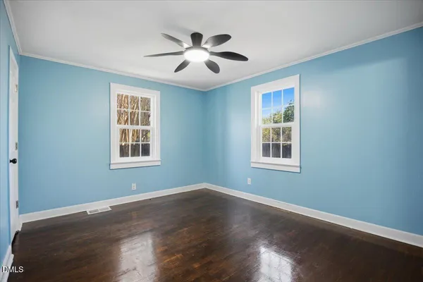 a view of empty room with wooden floor and fan