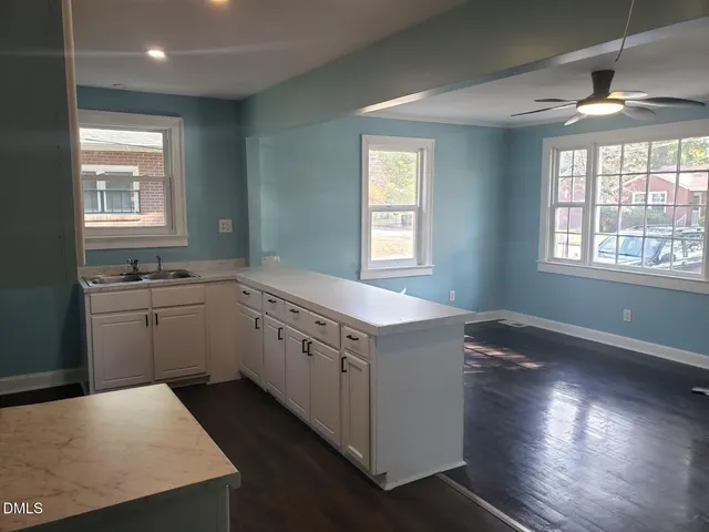 a kitchen that has a sink a stove and wooden floor