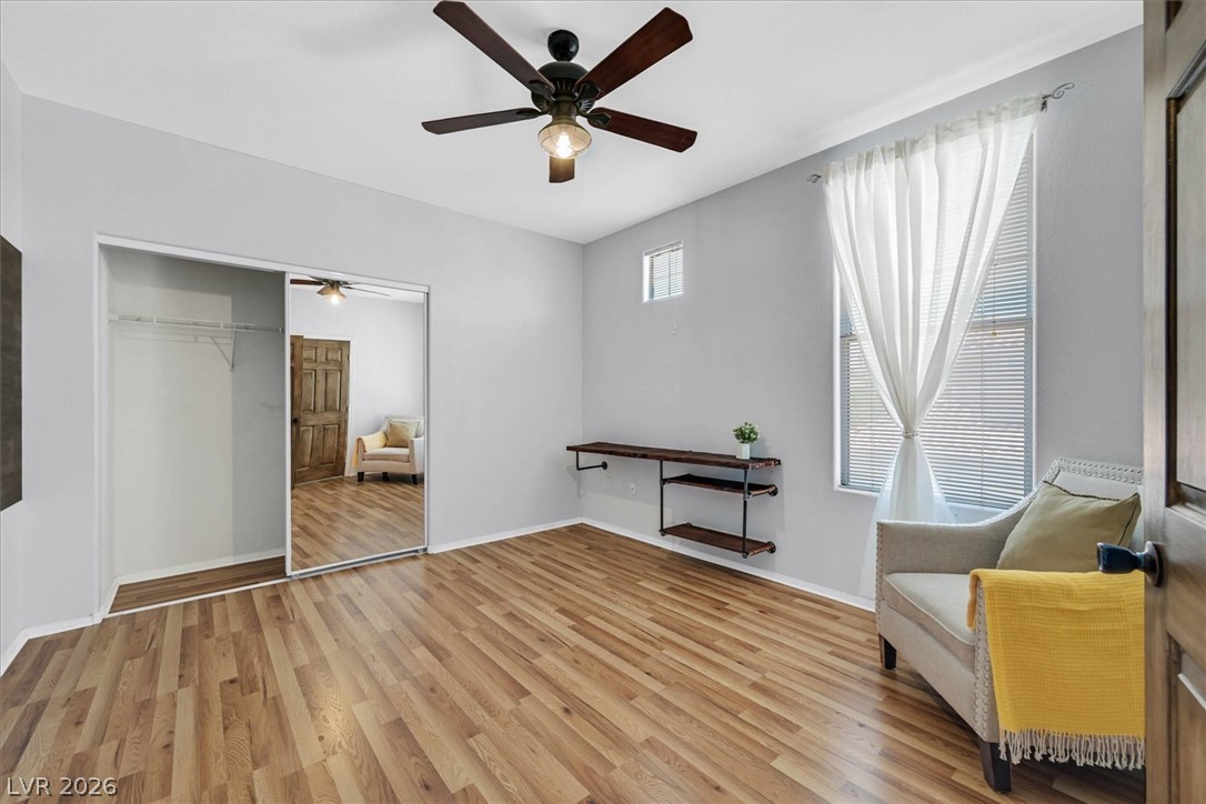 8555 West Russell Road, Unit 2069 Las Vegas, NV 89113 - Photo 13 of 27 A well-lit bedroom features hardwood floors and a ceiling fan, with mirrored closet doors reflecting the space.