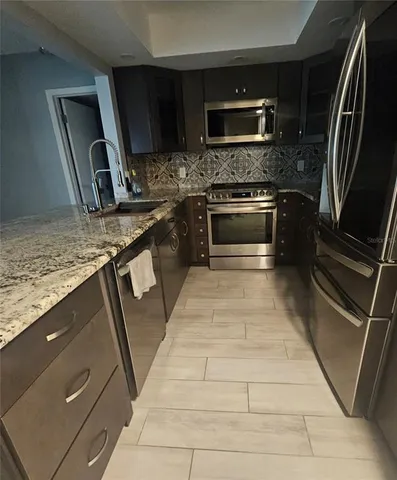 a kitchen with granite countertop a stove a microwave a sink and a counter top space