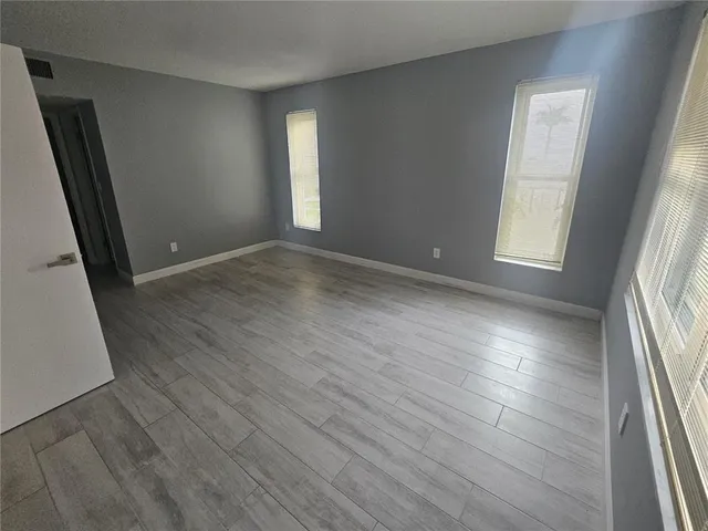 an empty room with wooden floor and windows