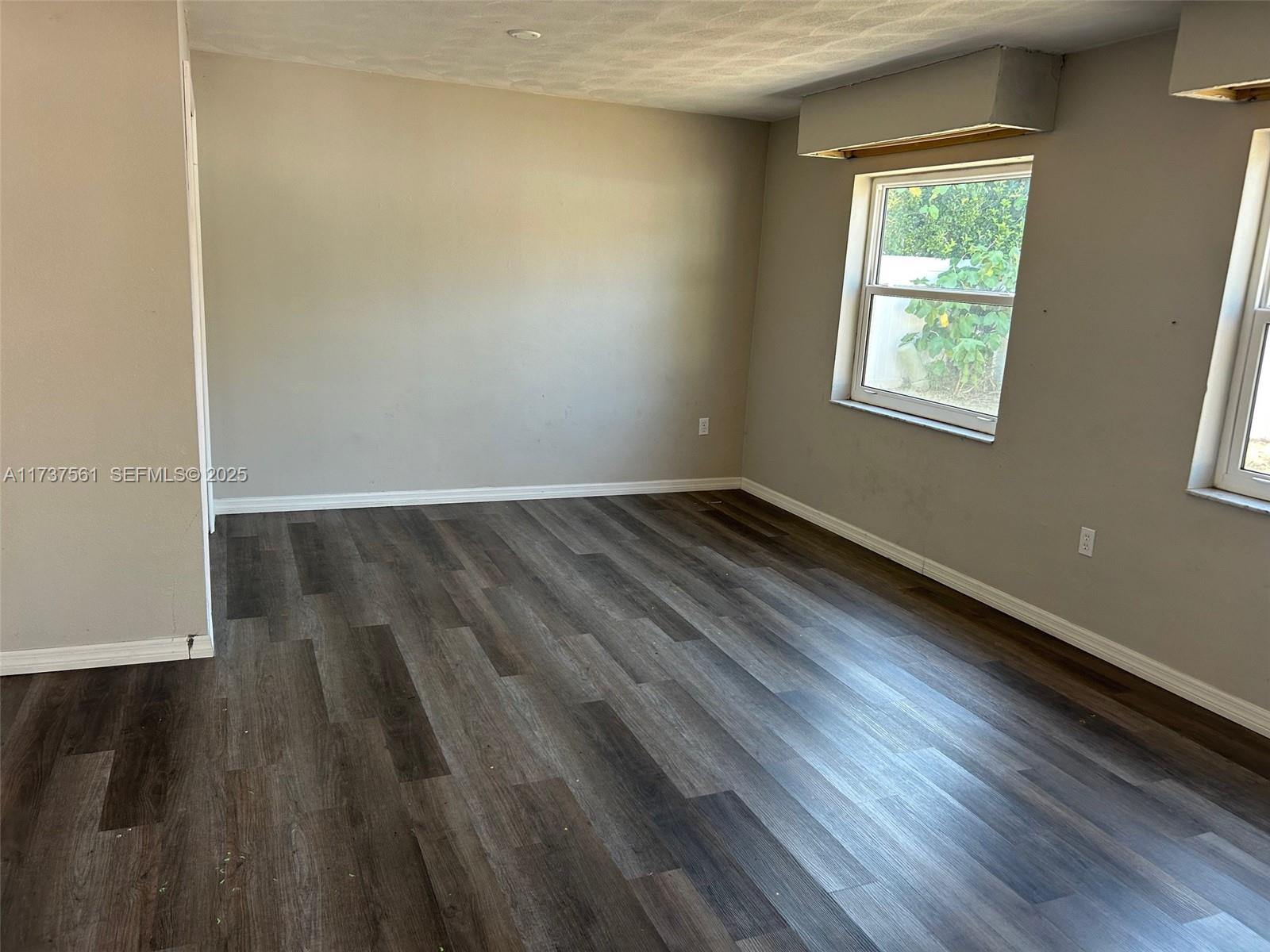 7403 Foxbloom Drive Port Richey, FL 34668 - Photo 22 of 45 an empty room with wooden floor and windows
