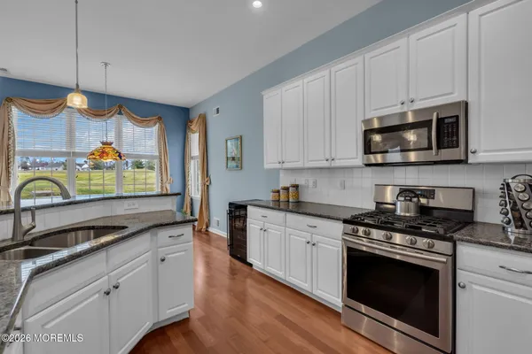 a kitchen with stainless steel appliances granite countertop a sink a stove a microwave and wooden cabinets