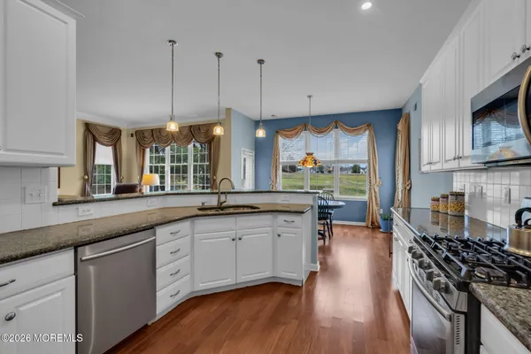 a kitchen with stainless steel appliances granite countertop wooden floors a stove and a wooden floors