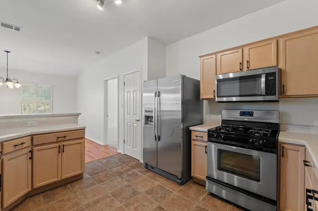 a kitchen with cabinets stainless steel appliances and wooden floor