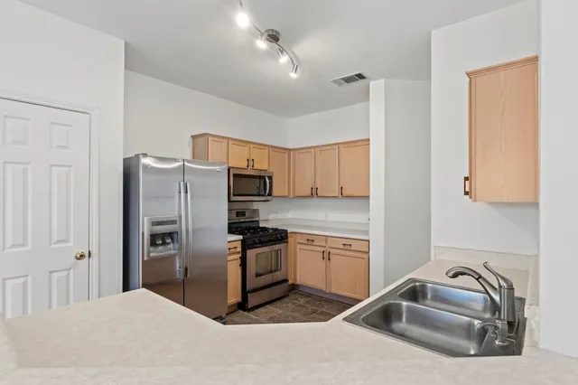 a kitchen with stainless steel appliances granite countertop a sink refrigerator and cabinets