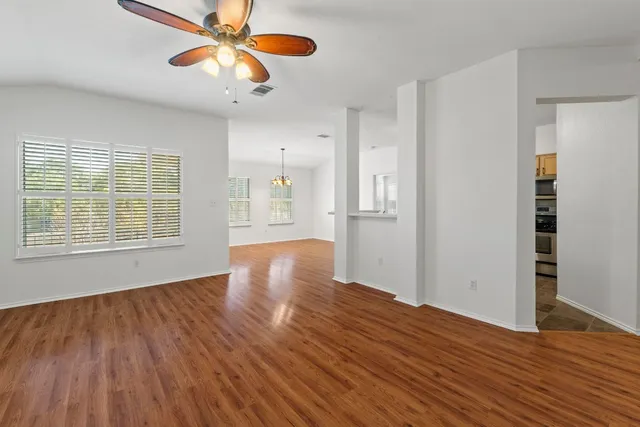 a view of an empty room with window and wooden floor