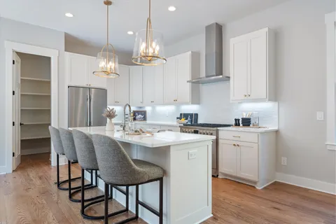 a kitchen with kitchen island a sink stove and white cabinets