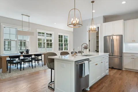 a kitchen with stainless steel appliances granite countertop a dining table chairs stove refrigerator and cabinets