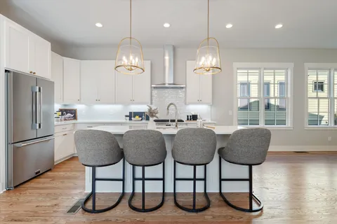 a kitchen with stainless steel appliances granite countertop a dining table chairs sink refrigerator and microwave