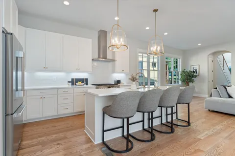 a kitchen with stainless steel appliances granite countertop a sink a stove a refrigerator and island with wooden floor