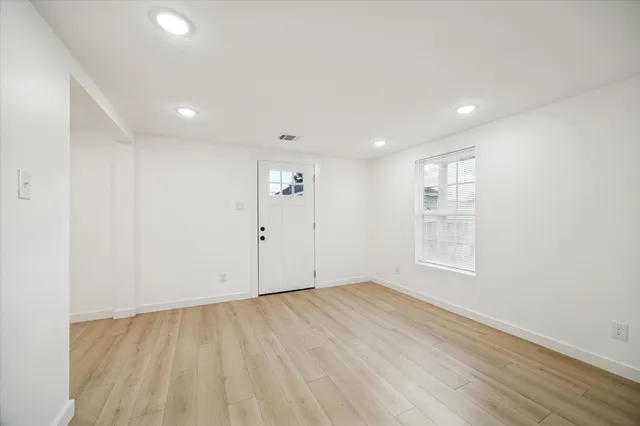 an empty room with wooden floor and windows