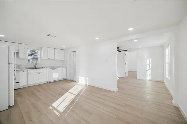a large white kitchen with white cabinets and wooden floor