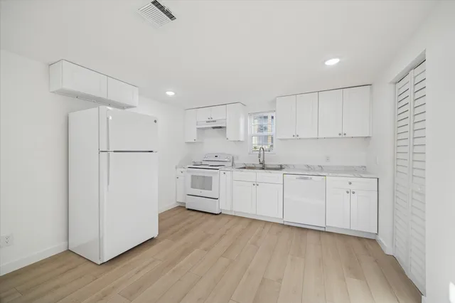 a kitchen with white cabinets and white appliances