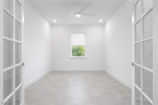 an empty room with a window and ceiling fan